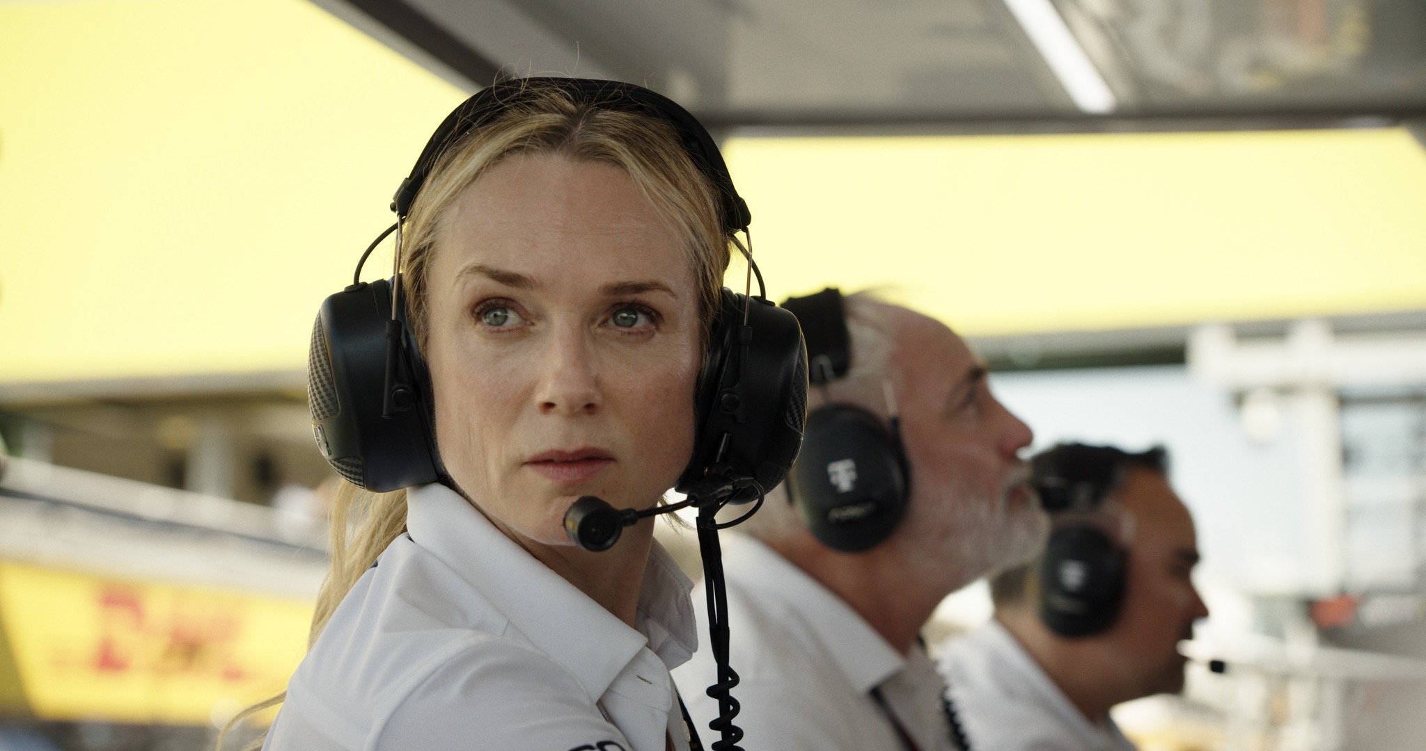 Actress Kerry Condon, as Kate McKenna, wears headphones and looks intently during a race